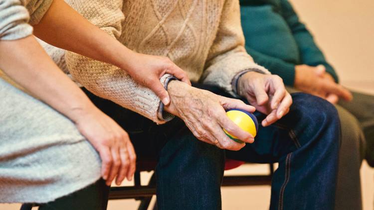Eldery person sitting on a chair and holding a bal
