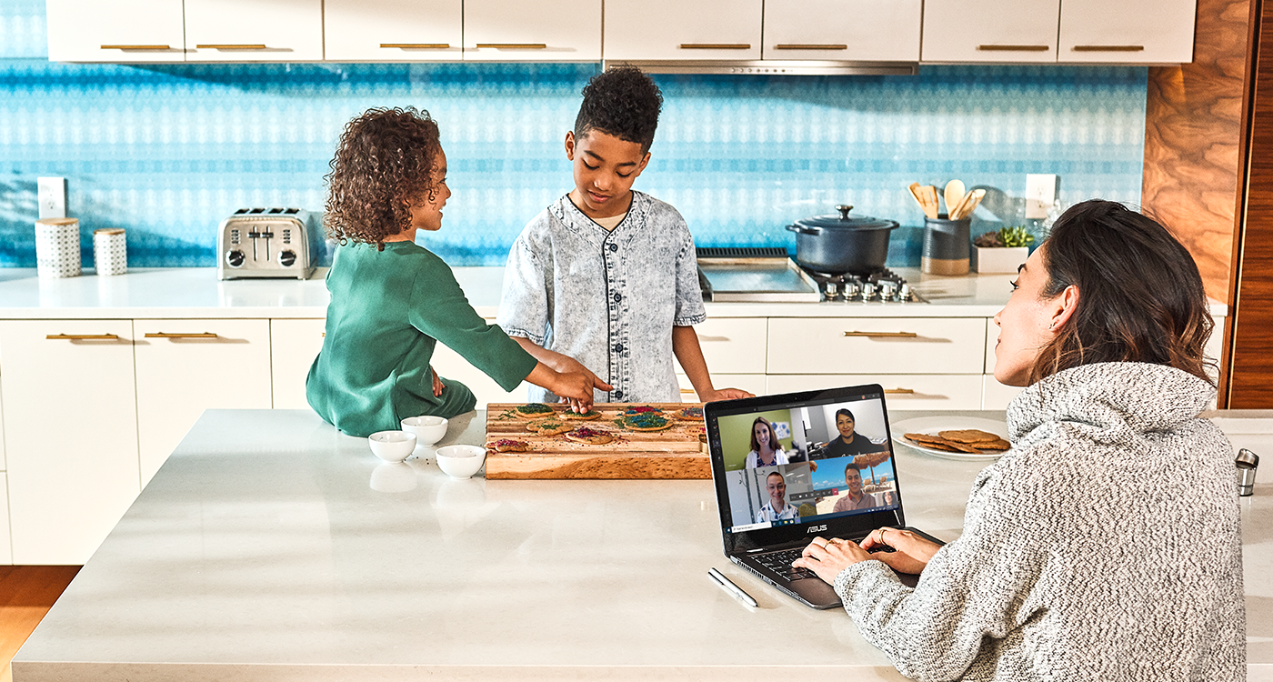 Woman working from kitchen with 2 kids in the background