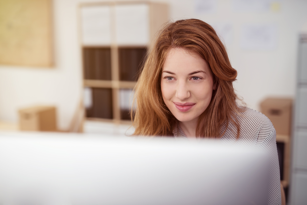 Smiling woman looking at computer monitor