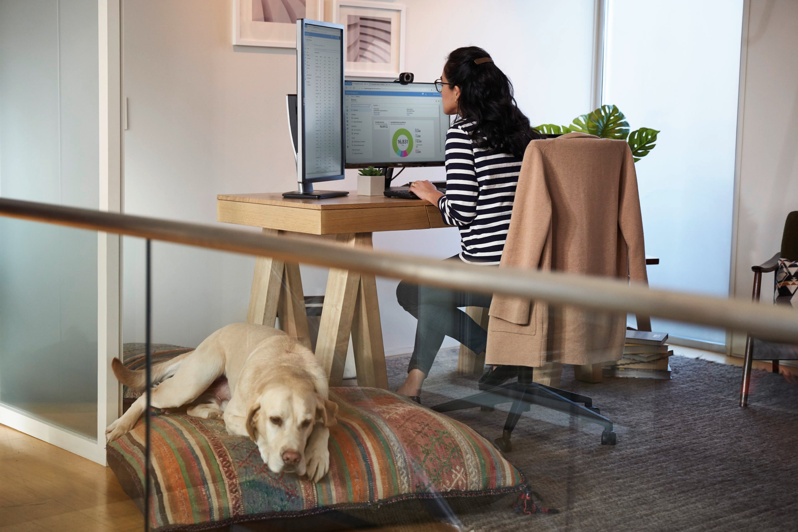 Woman working from her home office with dog next to her on the floor